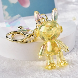 Detail of yellow iridescent space bunny keychain with mechanical design and golden ring