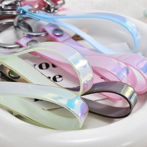 Detailed view of colorful laser PVC wristlets with silver metal clasps in a white bowl