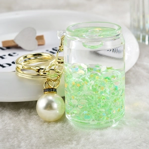 Detailed shot of a green liquid quicksand keychain with gold hardware and large pearl charm