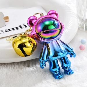 Macro detail of gradient electroplated astronaut bear keychain with gold bell accessory