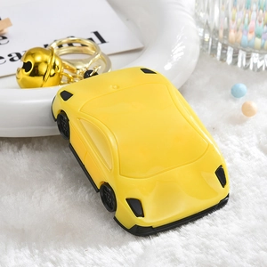 Cute yellow sports car keychain accessory with golden bell and metal clip on white tray
