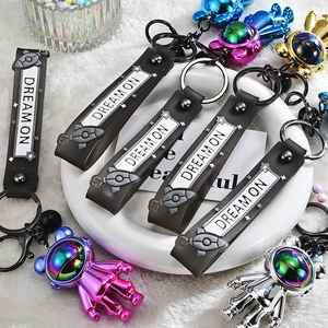 Macro view of metallic astronaut keychains with iridescent finish and Dream On silicone straps