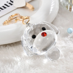 Crystal clear puppy keychain with gold lobster clasp on white faux fur background