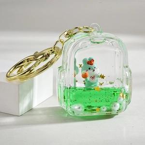 Close-up of green mini backpack keychain with liquid glitter sand and a small bunny