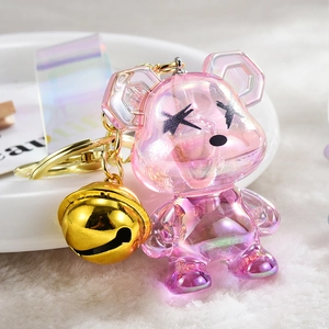 Makroansicht des pinkfarbenen Kristallbären-Schlüsselanhängers mit goldener Glocke