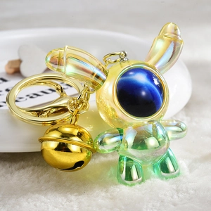 Macro shot of a gradient acrylic astronaut bunny keychain with gold bell and metallic ring