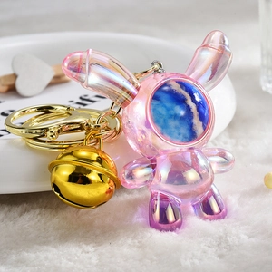 Macro shot of pink gradient acrylic bunny keychain with gold bell and astronaut mask