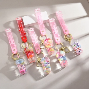 Colorful fruit bear milk tea cup keychains with liquid sand and cute charms on a desk