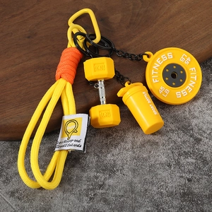 Détail du porte-clés fitness jaune avec disque de musculation, haltère et shaker