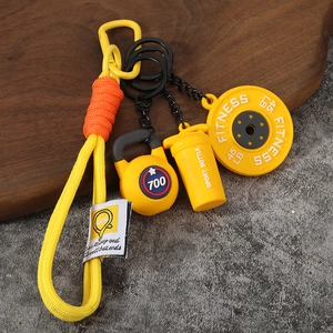 Détail du porte-clés disque d'haltère jaune avec kettlebell et lanière tressée assortie