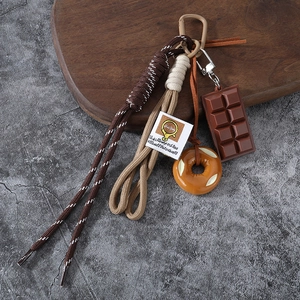 Brown braided rope keychain with realistic chocolate and donut charms on wooden background