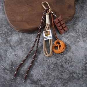 Maillard-style pretzel keychain with chocolate charm and brown braided rope on wood