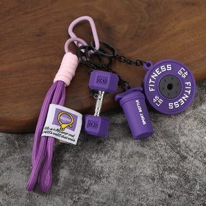 Détail porte-clés fitness violet avec haltère, disque de poids et bouteille sport