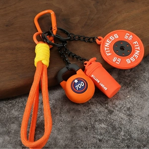 Détail d'un porte-clés fitness orange avec disque d'haltère, kettlebell et gourde sport