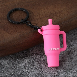 Pink tumbler shaped keychain with Persist text and black metal ring on wooden surface