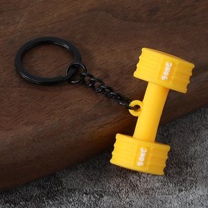 Detailed close-up of a yellow mini dumbbell keychain with textured grip and black ring