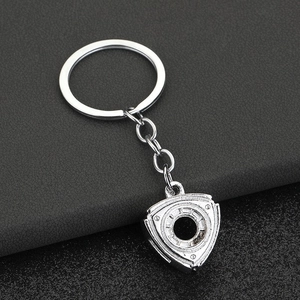 Silver metallic rotary engine keychain pendant on dark leather background