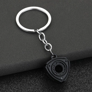 Macro shot of matte black rotary engine rotor keychain on dark leather surface