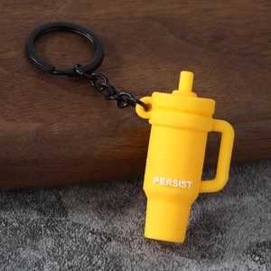 Macro shot of bright yellow mini cup keychain with Persist text and black metal ring