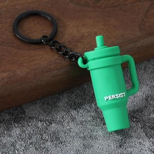 Macro detail of a green mini cup keychain with PERSIST text on a textured wooden background