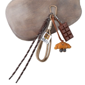 Maillard style pretzel keychain with chocolate bar and smiling croissant charms on wood