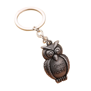 Vintage metal owl keychain with 3D embossed Good Luck text on white background