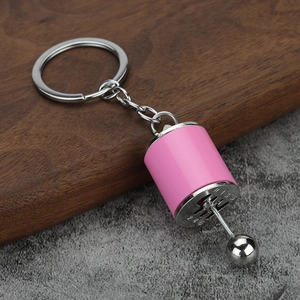 Close-up of pink manual gear shifter keychain with movable lever on wooden surface