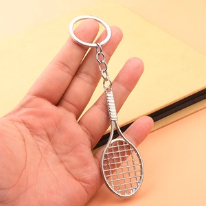 Hand holding a miniature silver tennis racket keychain with realistic string details