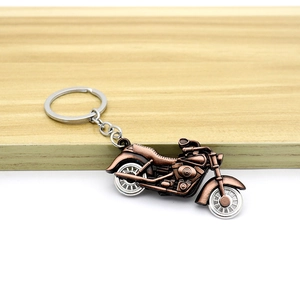 Detailed close-up of motorcycle keychain with movable wheels in bronze vintage style