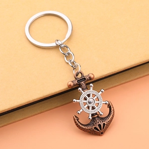 Vintage bronze nautical anchor keychain with rotatable silver ship wheel on dual-tone background