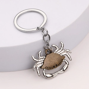 Crab shaped metal keychain with bronze shell and silver legs on a display stand