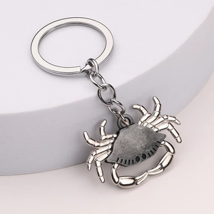 Silver metal crab keychain with vintage texture on a white display stand