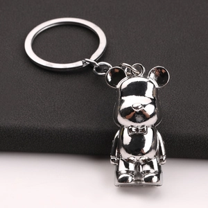Polished silver metal bear keychain with bow tie detail on a textured leather background