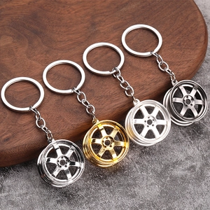 Set of four alloy car rim keychains in silver, gold, white and grey on wooden tray