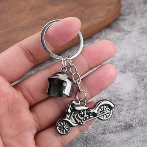 Macro detail of vintage metal motorcycle and helmet keychain charms in antique silver