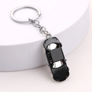 Sleek black car-shaped keychain with silver metal ring on a minimalist white stand