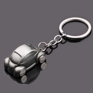 Vintage silver metal car keychain with classic sedan design on reflective black background
