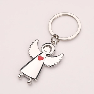 Silver metal angel wing keychain with a red heart pendant on a gray background