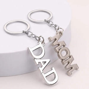 Polished zinc alloy DAD and MOM letter keychains on a modern minimalist display