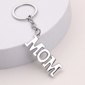 Polished silver metal MOM letter keychain with reflective finish on white pedestal