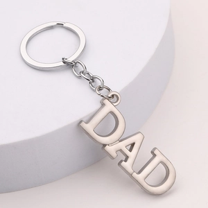 Zinc alloy DAD letter keychain with polished silver finish on a white display stand