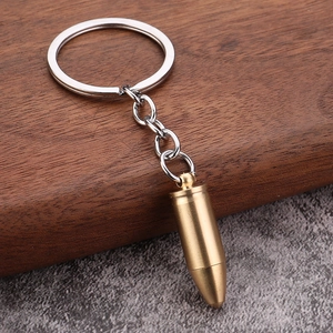 Close-up of brass bullet keychain with textured metal finish on a dark wood background