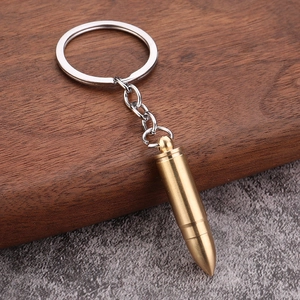 Macro detail of brass bullet-shaped keychain on natural wood and stone background