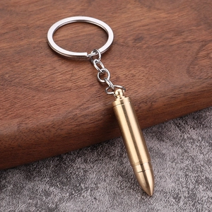 Detailed view of a brass bullet-shaped keychain on a wooden surface with metal ring