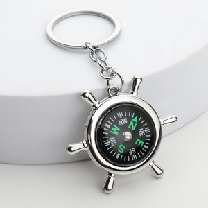 Macro view of silver alloy ship helm compass keychain with polished metallic finish