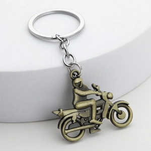 Porte-clés moto vintage en bronze présenté sur un socle en pierre blanche
