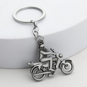 Porte-clés motard vintage en argent antique sur un présentoir de produit blanc