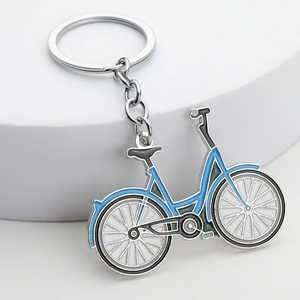 Silver bicycle keychain with blue enamel details on white minimalist display background