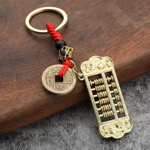 Golden abacus keychain with traditional Chinese coin and red cord on a dark wood background