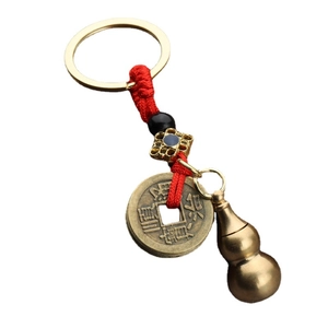 Brass gourd keychain with ancient coins and red braided rope on a white background